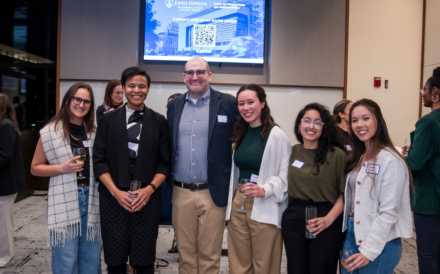 Six members of event crowd stand and smile at the camera.
