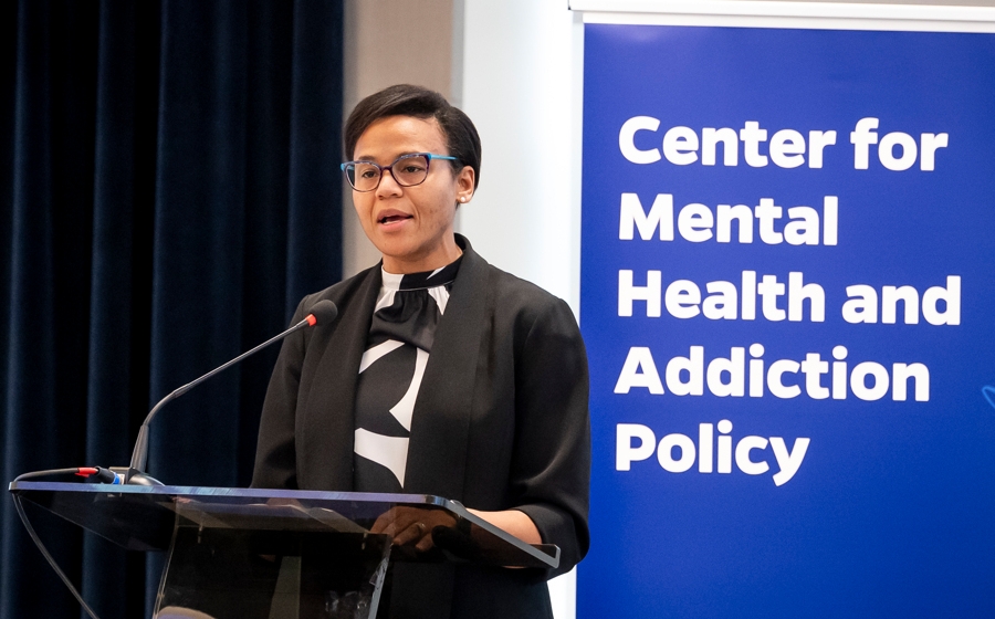 A woman in business attire stands behind a podium.