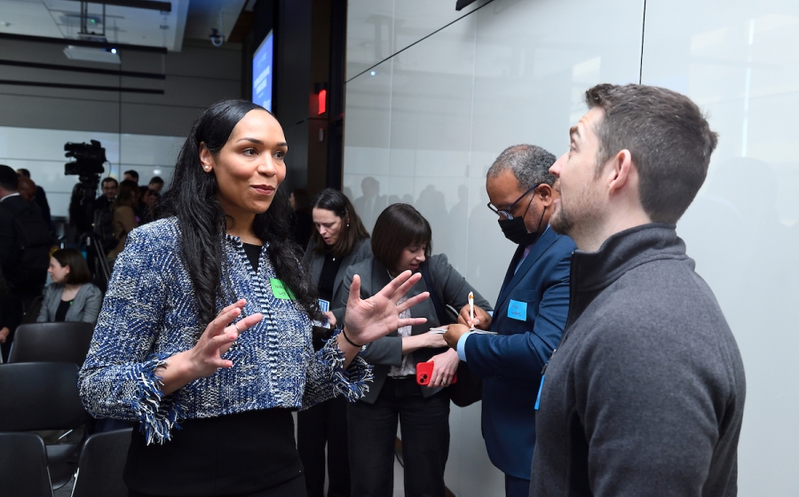 A woman and a man converse among a crowd.