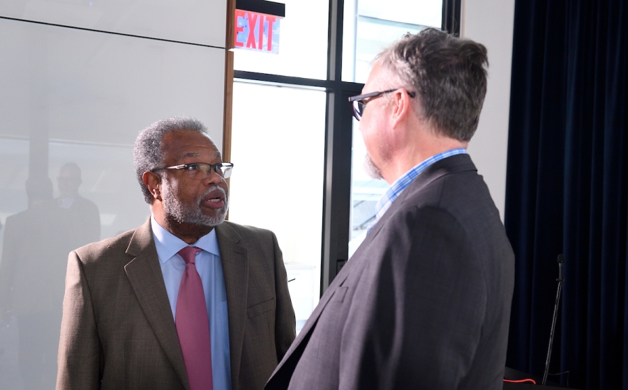 Two men dressed in business attire converse.