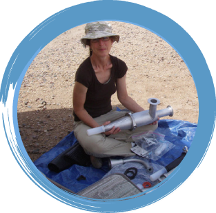 Alison Geyh practice award Smiling woman sitting on ground holding a piece of air monitoring equipment