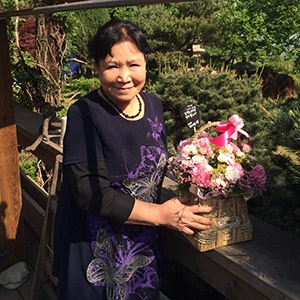 Dr. Kim stands outside on a porch, holding a floral arrangement Dr. Kim holds a floral arrangement while standing outside at her home in Seoul, South Korea