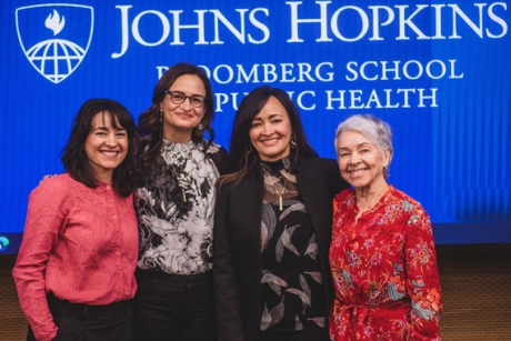 Four women stand together smiling: Melissa McMacken, Michelle McMacken, and Marisol Renner, and their mother Maria McMacken