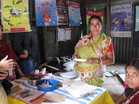 Photo of Community Health Research Worker preparing to administer vaccine to an infant