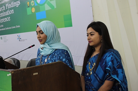 Two women in blue tops stand at a podium