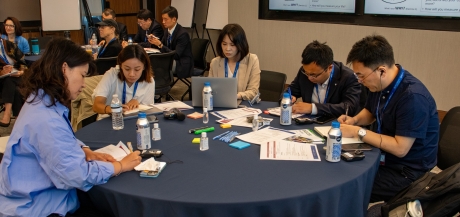 A group of people working around a table covered by a blue tablecloth
