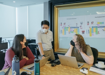 Implementation Science researchers working around a table with lap tops at a Human Centered Design Workshop in Indonesia.