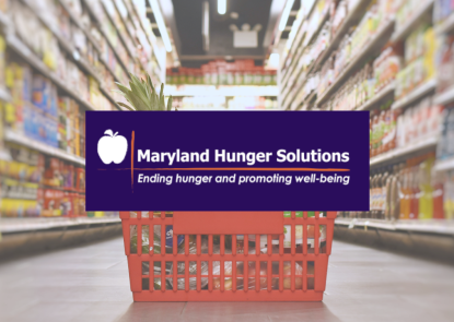 grocery basket sitting on the floor in a grocery store aisle with Maryland Hunger Solutions logo 