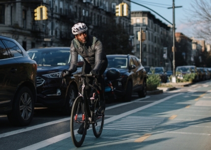 man riding bike next to parked cars