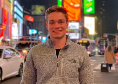 Young man standing outside on busy street