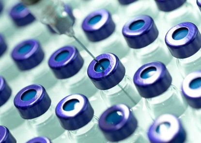 Rows of blue capped vials, with a syringe needle pearced into one