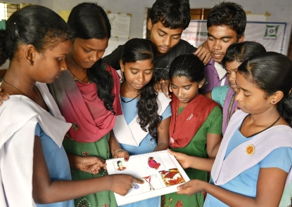 a group of teenage girls and boys look at a reproductive health book