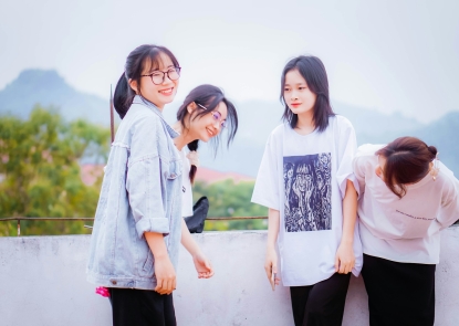 A group of four adolescent girls smiling in front of a mountain landscape