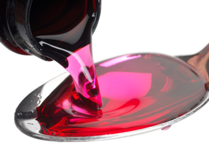 Pink cough syrup being poured into a spoon